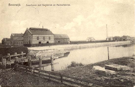 Zwaaihaven met Gasfabriek en Marmerfabriek
In vroeger jaren maakte het Gasbedrijf zelf gas, later leverde Hoogovens cokesgas dat door het Gasbedrijf werd doorverkocht. Vandaar de naam Gasfabriek en menigeen zal zich dat nog herinneren. Gas was belangrijk, de verlichting in de huizen brandde er op en Beverwijk kende nog heel veel jaren, zelfs tot ver na de 2e wereldoorlog, straatverlichting welke op gas brandde. Door de komst van de Velsertunnel werd het Gasbedrijf verplaatst, kwam in later jaren te liggen op de plaats waar onlangs &quot;Woon Plaza&quot; is gebouwd. Want door de komst van het aardgas werd het Gasbedrijf overbodig en werden de gebouwen gesloopt. Op de kaart helemaal rechts zijn de gebouwen te zien van de Chemische Fabriek Noord-Holland, kortweg de vismeelfabriek genoemd. De restanten werden na een fikse brand opgekocht door de gemeente.
Keywords: de pijp haven bwijk