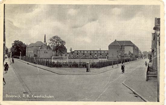 Kees Delfsweg
Op de ansichtkaart zien wij de hoek van beide straten met een uitzicht op wat tegenwoordig de PA-driehoek wordt genoemd. De kaart moet dateren uit rond 1950. De tekst onder de ansichtkaart luidt: R.K.Kweekscholen en dat is wat overdreven. De oorsprong van het complex ligt wel in de bouw van de Bisschoppelijke Kweekschool in 1906 van de kapel behorende bij de school zien wij nog net het torentje. De kweekschool was een opleiding voor onderwijzers, die in de beginjaren ondergebracht waren in kosthuizen en later woonden in het internaat dat wij midden op de foto zien. Wij hebben voorts uitzicht op het sportterrein en links zien wij de R.K.Leerschool waar de kwekelingen praktijk konden opdoen. Rechts is het gebouw van de St.Willibrordus ULO, of te wel de MAVO. Na het vertrek van de Bisschoppelijke Kweekschool naar Bergen en de MAVO-school naar nieuwbouw aan de Dellaertlaan en niet te vergeten een aantal brandstichtingen werden de gebouwen gesloopt. Voor de R.K.Leerschool, ondertussen Sint Cassianusschool geheten, werd een nieuwe school gebouwd ongeveer op de hoek van beide straten, de oorspronkelijke naam de Populier is ondertussen gewijzigd in de Wilgeroos.
Keywords: bwijk Kees Delfsweg