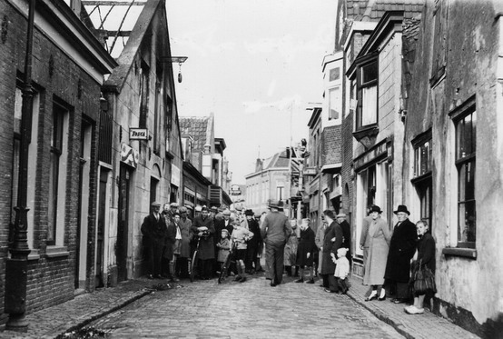 Begijnenstraat
Begijnenstraat middengedeelte. Geheel rechts de smederij van Brouwer. Het gebouw waar de groep mensen voor staan is de Groentehal van Dirk Maks.
Keywords: bwijk begijnenstraat