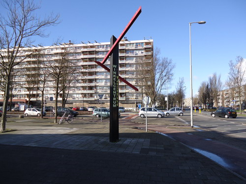 Monument beschilderd staal
Gerard Hali behoorde ooit tot de groep Heemskerkse kunstenaars die in de atelierruimte van de Mariaschool actief was. Daar werkte hij vooral met hout waar van hij meestal grote open objecten en sprookjesachtige machines maakte. Werkwijze, materiaalkeuze, alles ging op de schop toen Gerard Hali in 1980 zijn eerste opdracht voor een buitenkunstwerk kreeg. Opdrachtgever was winkeliersvereniging De Wijkerbaan die het winkelierscentrum graag opgesierd zag met een kunstwerk. Vanaf die tijd is Hali met staal gaan werken. Tenminste, hij liet zijn ontwerpen door een constructie uitvoeren. Hij beheerste die techniek immers zelf (nog) niet. Samen met het voor hem nieuwe materiaal heeft dat tot een drastische versobering van zijn werken geleid. Dat is goed te zien aan dit eerste stalen buitenbeeld dat zijn beeldende kracht vooral aan het telkens optisch veranderd effect ontleend.    

Bron: Blik op Beeld, Tekstbureau Zonneveld & Thöne i.o.v. gemeente Beverwijk, 2006.
Foto en bewerking: Co Backer

Keywords: bwijk Openbare Kunstwerken